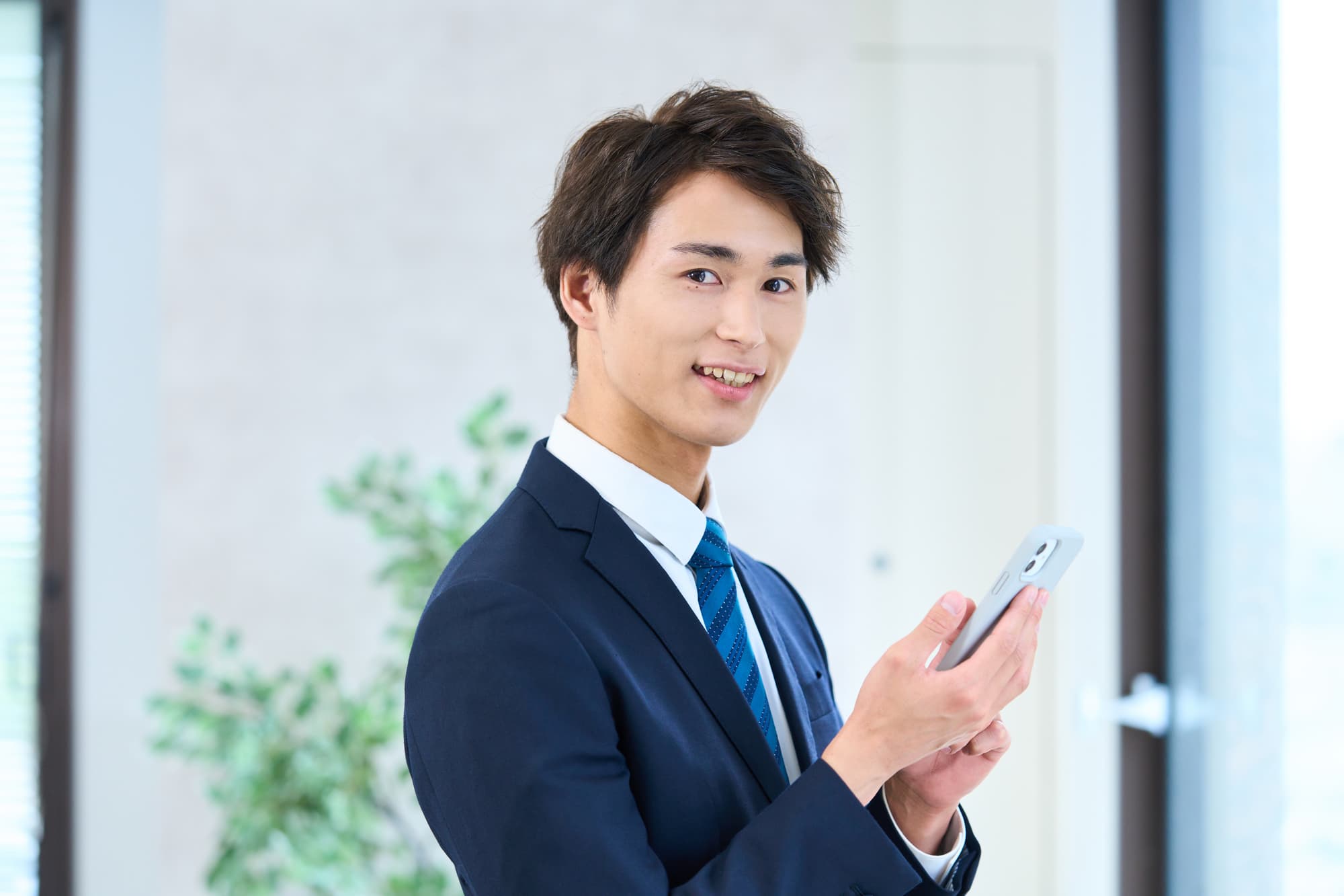 顎関節症が治って微笑むスマホを手にしたサラリーマン