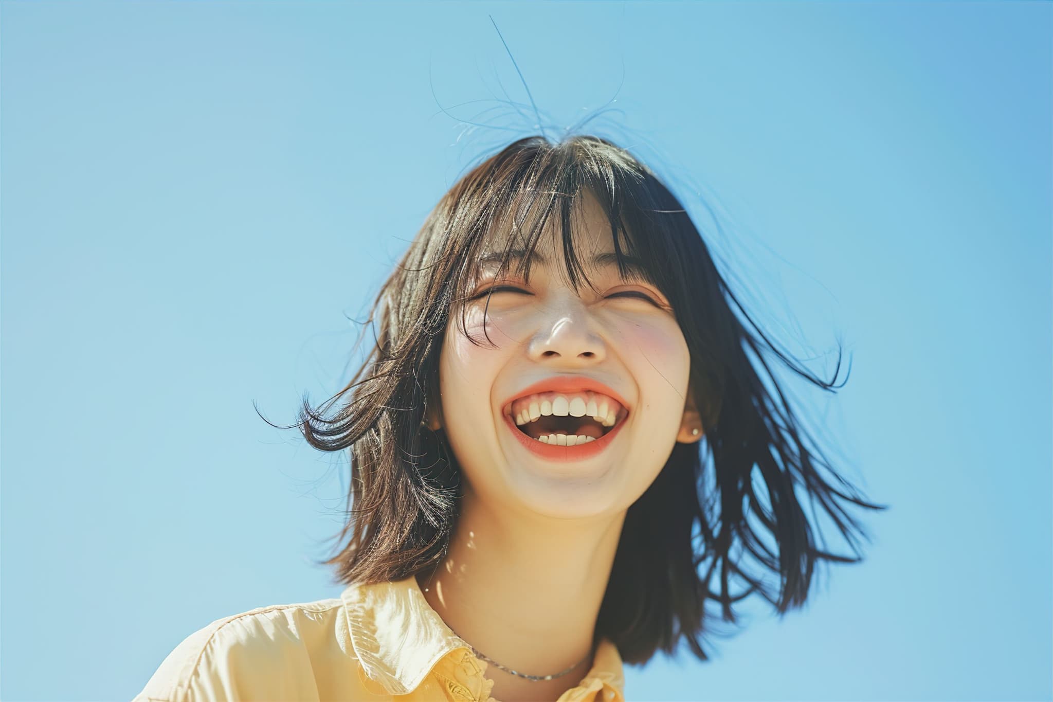 審美歯科で美しくなった前歯に満足して笑う女性