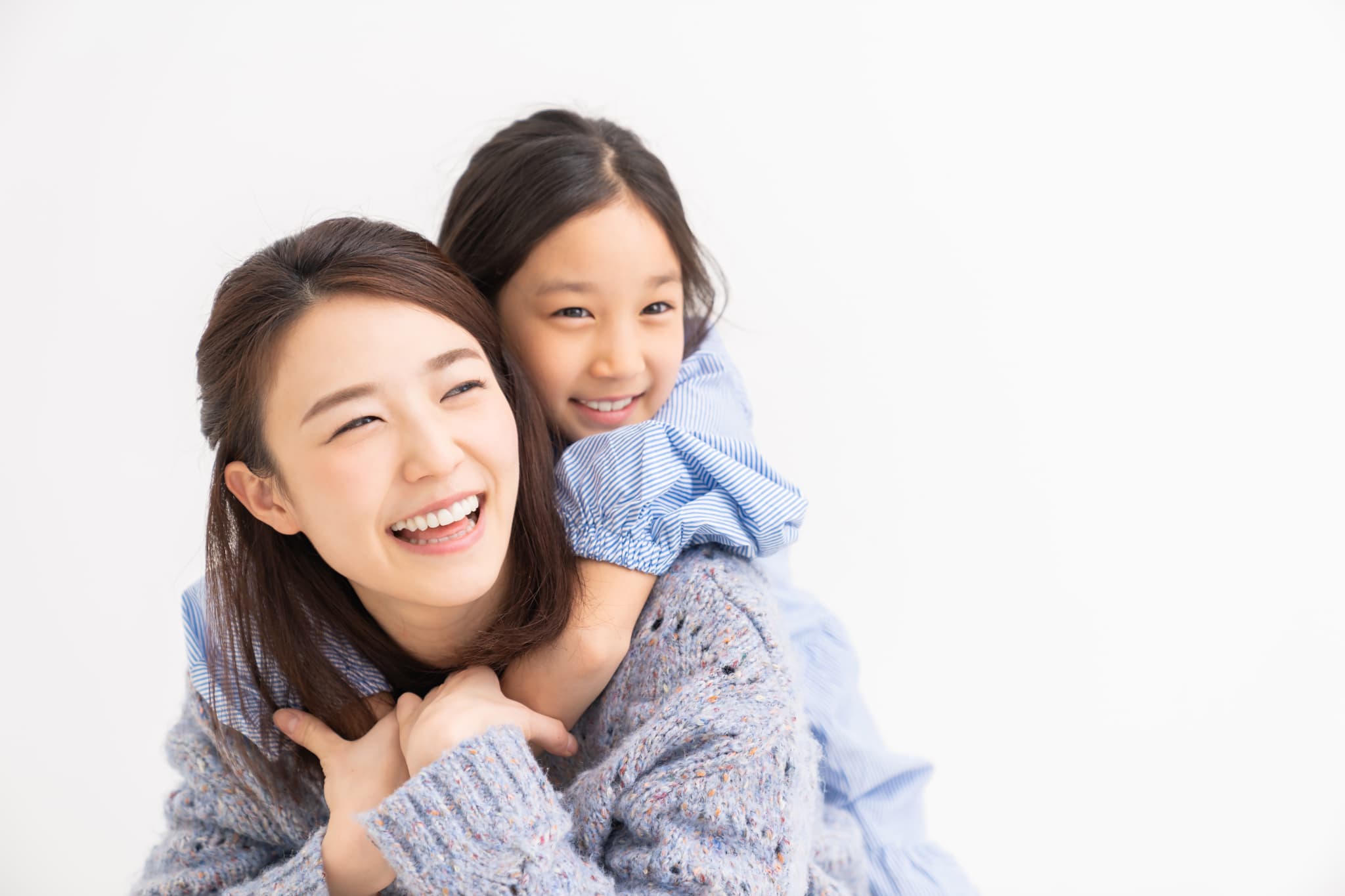 小児矯正で整った歯並びになった子どもを背負って笑う母親
